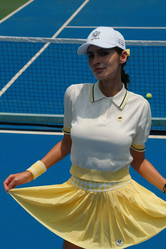 Woman in a white and yellow tennis outfit on a blue tennis court