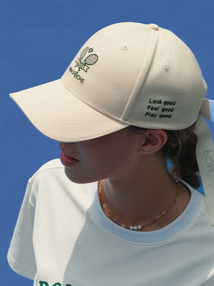 Ivory tennis baseball cap with embroidered Pom Pêche logo and detachable ribbon.