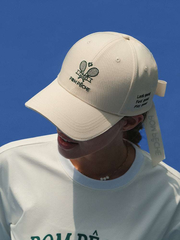 Ivory tennis baseball cap with embroidered Pom Pêche logo and detachable ribbon.