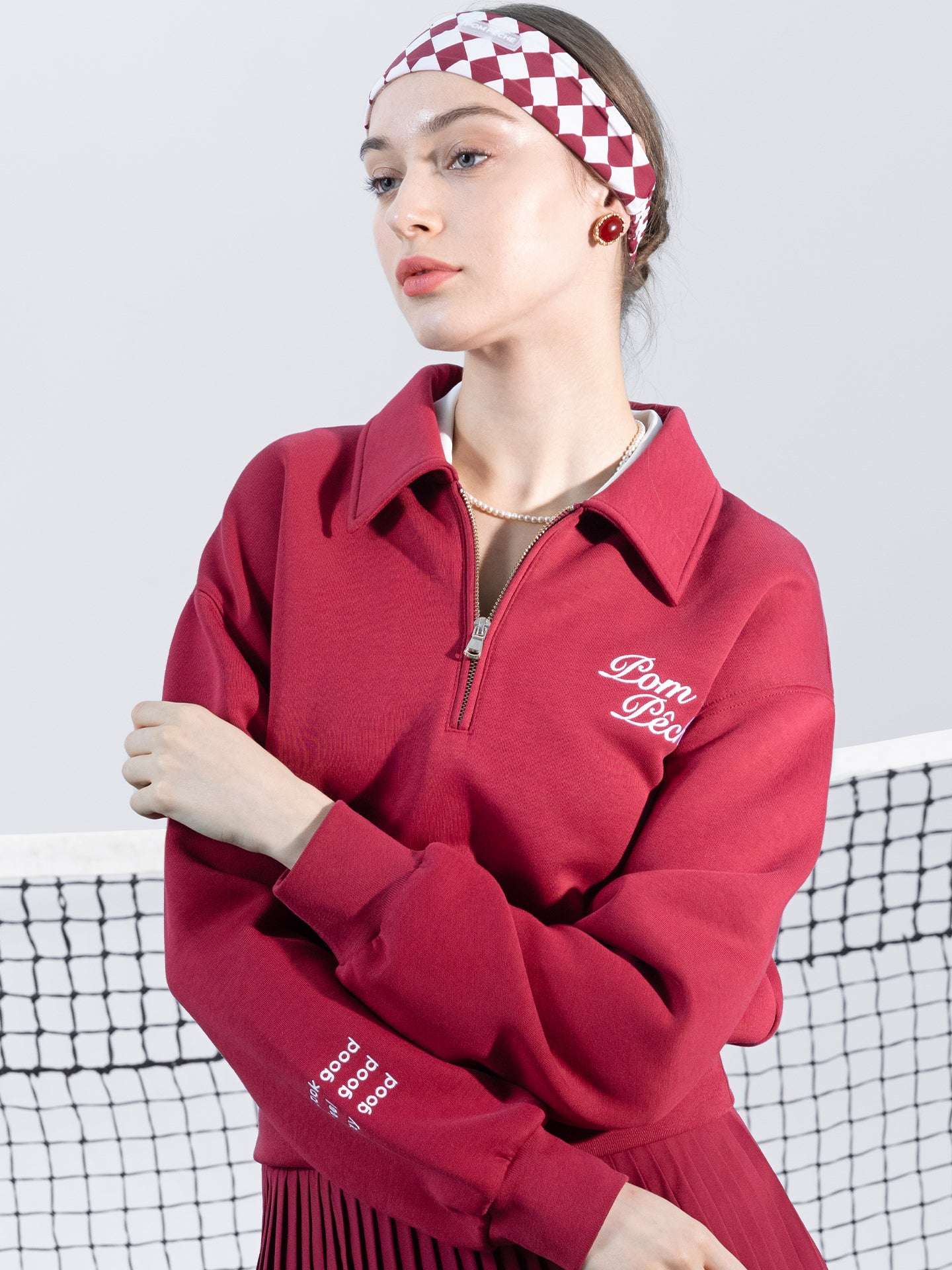 Red sweatshirt with quarter-zip design and embroidered logo on the front and back, offering a stylish and sporty look.