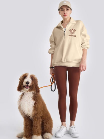 Person wearing a beige hoodie and brown leggings standing next to a dog on a white background